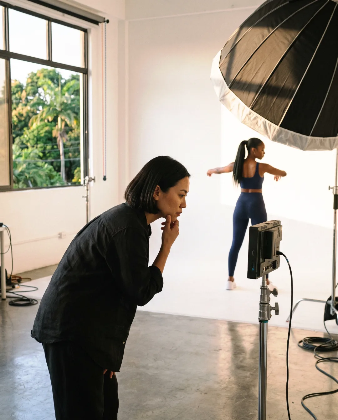 Creative director checking a frame while a model holds a pose in the studio