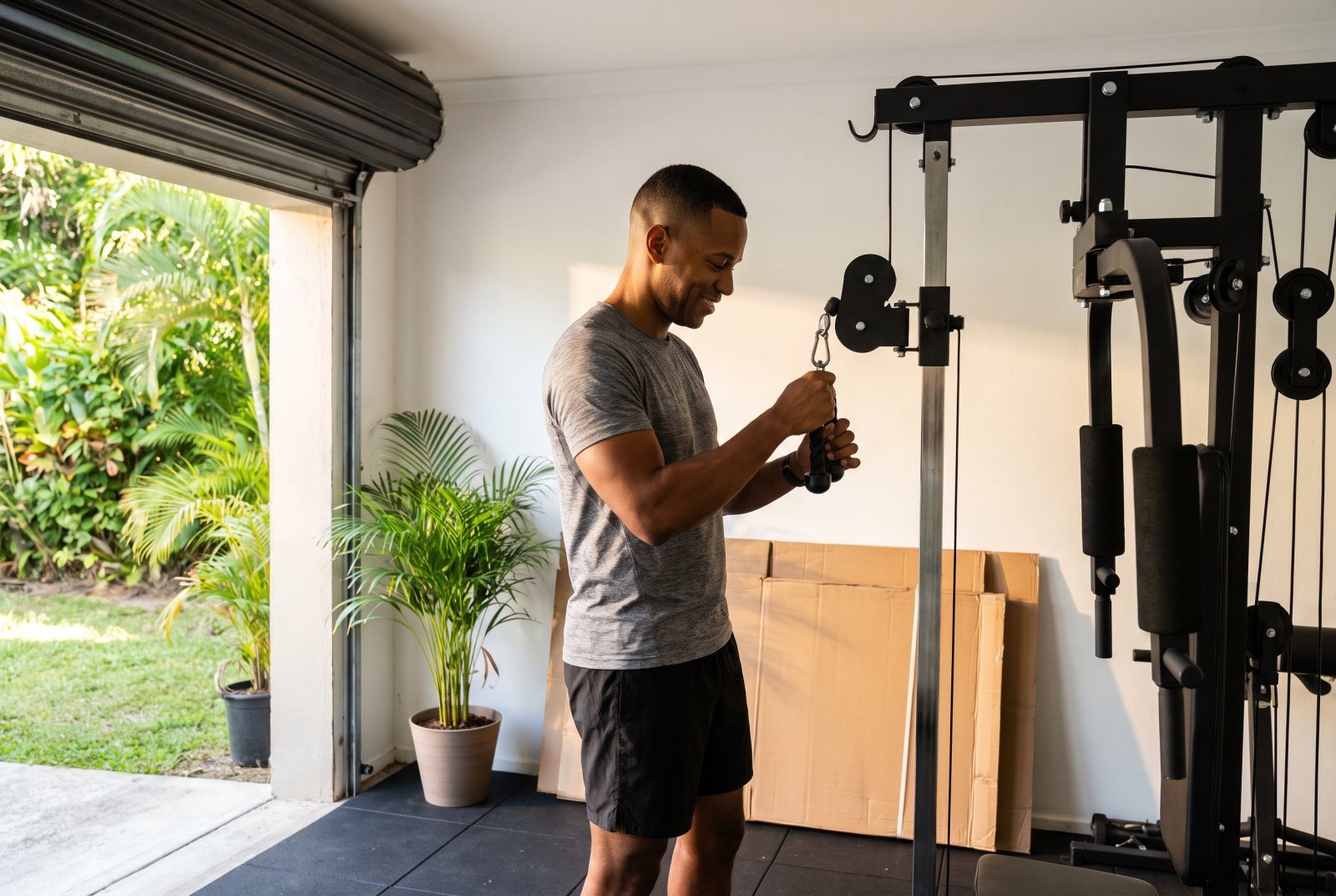 Man adjusting a newly assembled home multi-gym in a bright garage in Trinidad