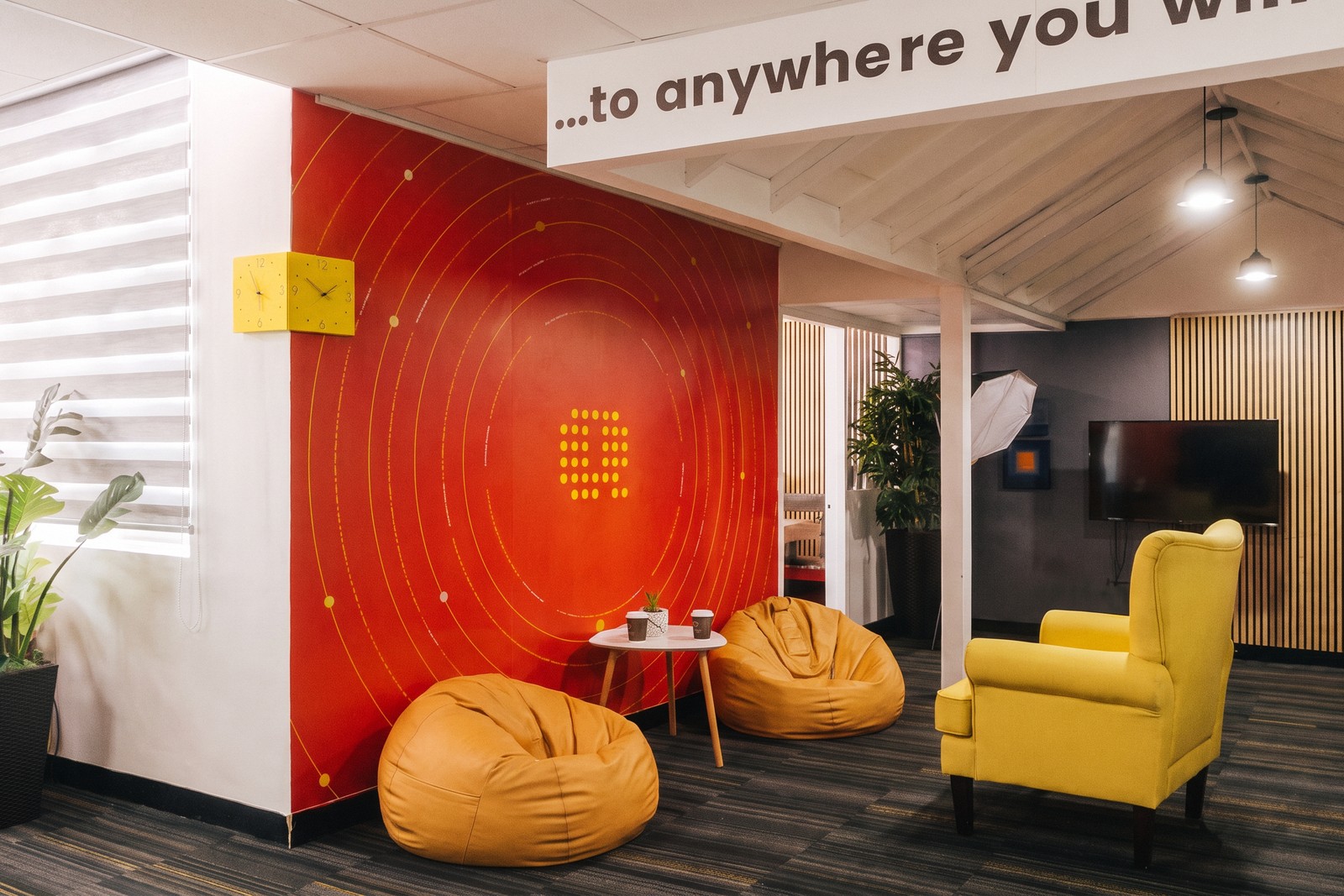 The Quoviz studio lounge in Trinidad, set up as a casual meeting corner with bean bags and a yellow armchair in front of the red Q wall